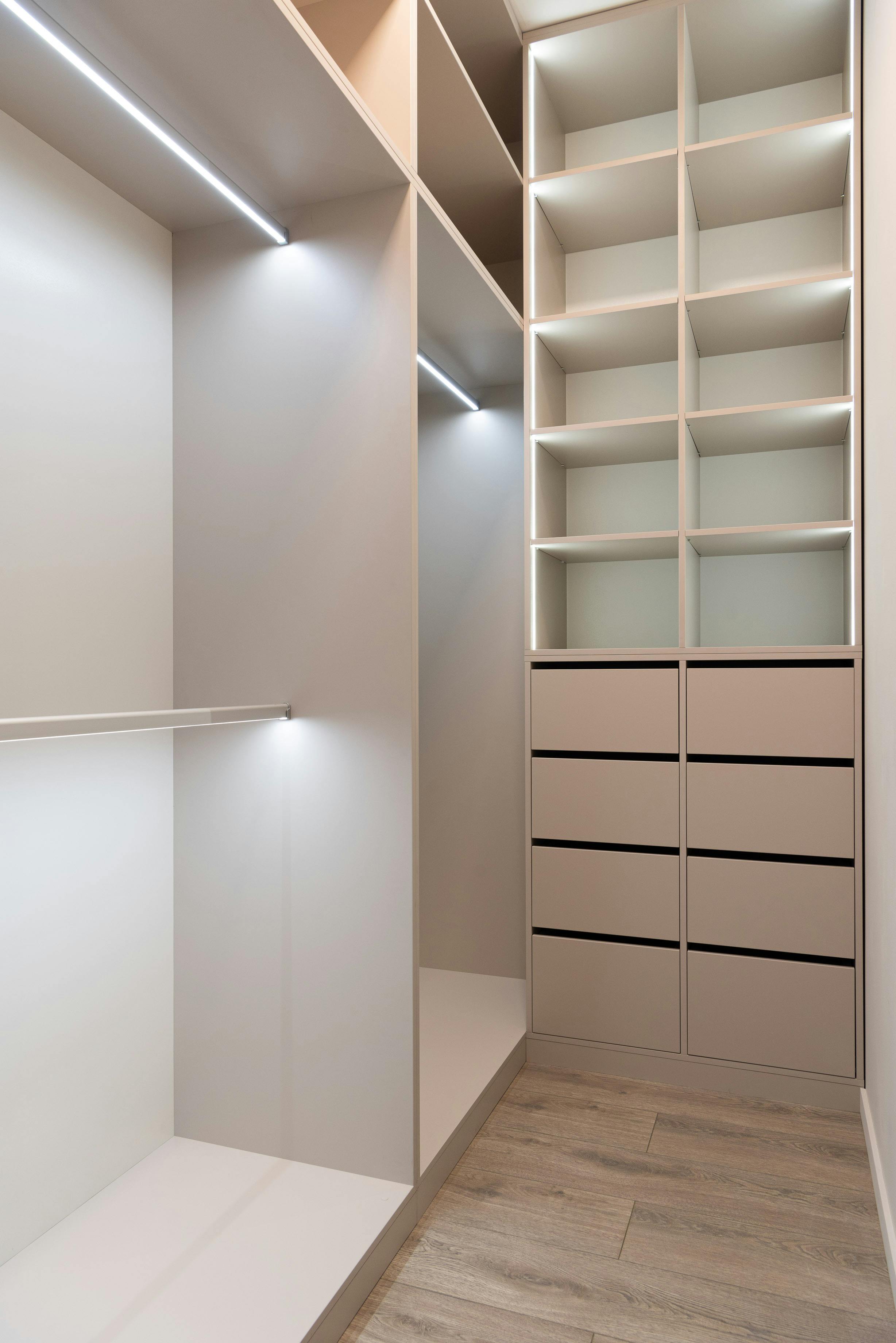 Luxury custom closet with full-height drawers, vertical shelving, LED hanging bar lighting, and upscale built-in storage features.